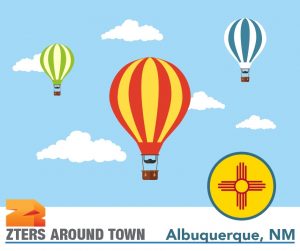 Albuquerque Balloon Fiesta depicted by 3 hot air balloons in different colors against a blue sky with clouds. ZTERS logo in bottom left.