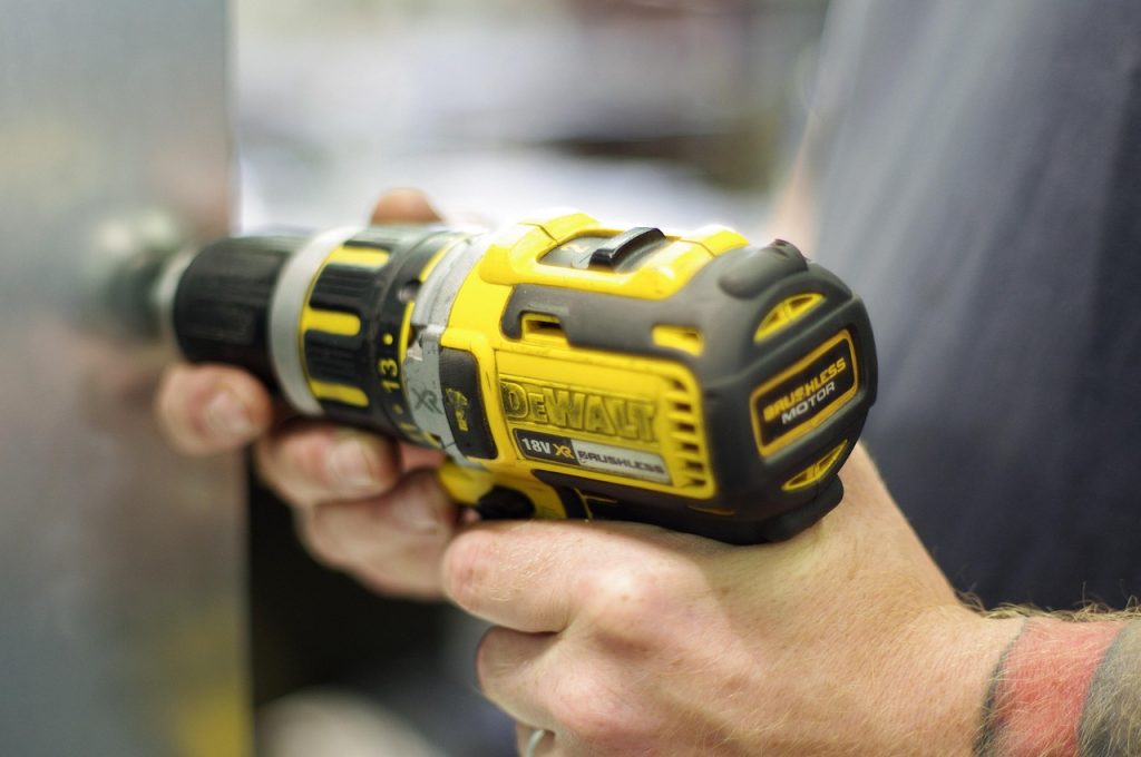 A picture of a person using a DeWalt cordless drill tool.