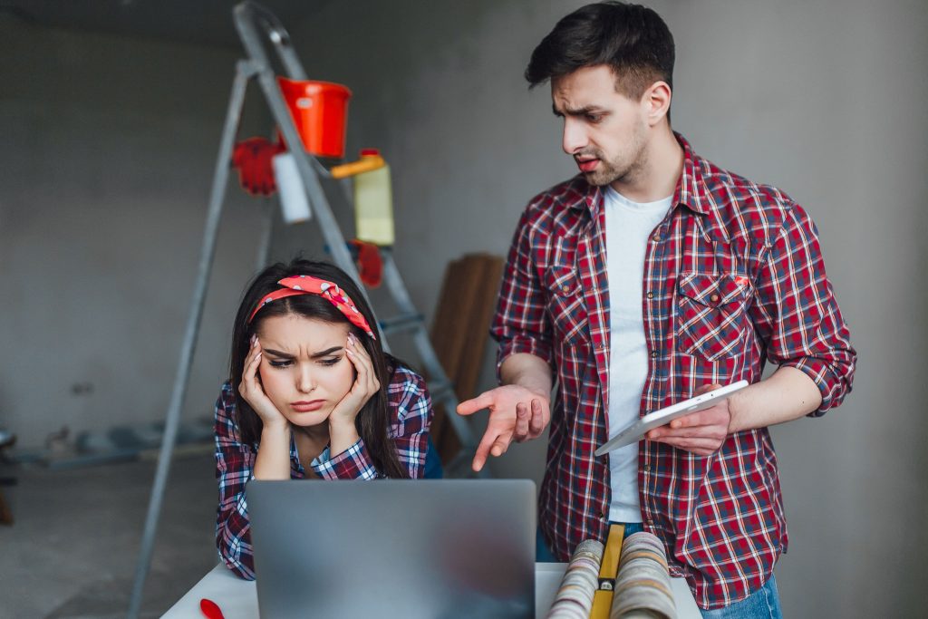 Home renovation mistakes to avoid illustrated by a stressed couple arguing over renovation planning and budget issues.