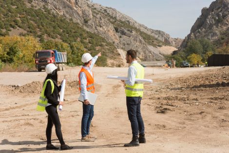 Contractors reviewing plans at a mountainous Arizona excavation site, illustrating the work involved when you become a general contractor in Arizona.