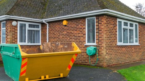 A photo of a small dumpster outside of a home.