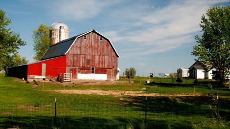A picture depicting long term porta potty rentals on a farm with an image of a red barn on a farm.