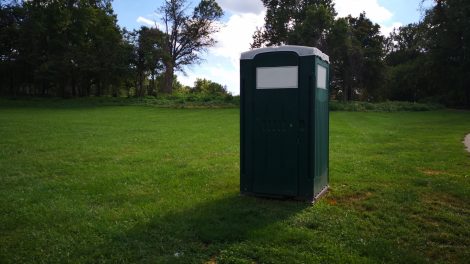 A picture of a porta potty on a farm.
